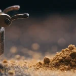 Golden Cannabis Kief Powder Next to a Metal Grinder