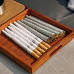 Mixed cannabis pre-rolls with different tips in a wooden box on a cozy surface.