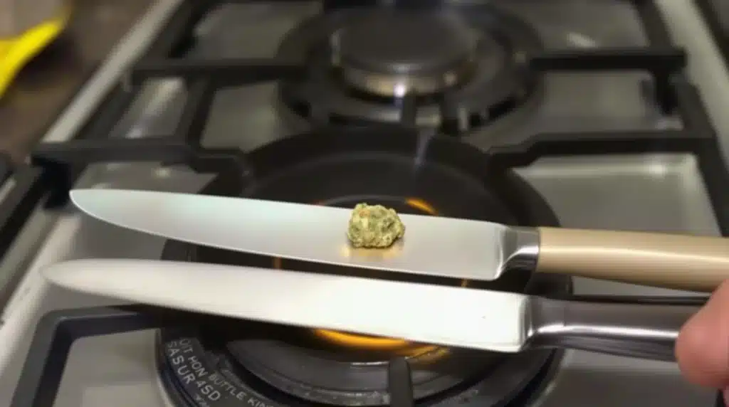 Heating butter knives on a stove for the hot knives method of smoking cannabis, in a kitchen environment.