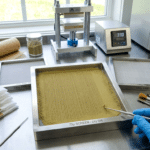 Dry sift screening lab workstation with micron screens, tools, collection bags, and sifted resin on a stainless steel table.