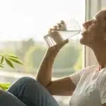 Realistic image showing a person using water to get rid of cotton mouth from weed, highlighting hydration after cannabis use.