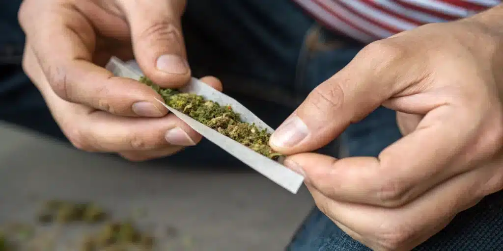 Realistic close-up of the rolling process for a spliff joint, highlighting the blend of tobacco and cannabis in the rolling paper.