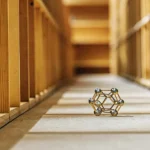 Metallic cannabis molecular structure model displayed on wooden floor.