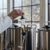 Close-up of a scientist handling cannabis oil in a syringe attached to an industrial extraction tank.