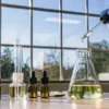 Lab setup with cannabis oil extraction tools and a gloved hand using a dropper.