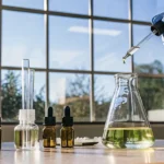 Lab setup with cannabis oil extraction tools and a gloved hand using a dropper.