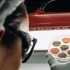 Scientist holding a Petri dish with six cannabis samples under red LED light.