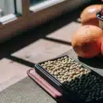 Tray of cannabis seeds with citrus fruits and berries by a window.