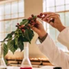 A scientist in a lab coat examining a sprig of red berries.