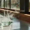 A steaming Erlenmeyer flask with a clear liquid on a lab bench.