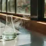 A steaming Erlenmeyer flask with a clear liquid on a lab bench.