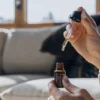 Person using a CBD oil dropper at home in a relaxed setting.
