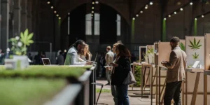 Visitors networking and exploring cannabis product displays at a large industry exhibition.