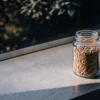 Feminized cannabis seeds stored in a transparent glass jar under natural light.