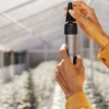 Grower adjusting a refractometer inside an indoor cannabis facility to prepare for brix level analysis.