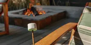 Cannabis-infused marshmallow on a wooden stick roasting near an outdoor fire pit at sunset