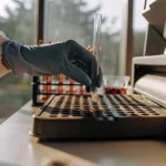 Gloved scientist placing a test tube into a laboratory analyzer for cannabis sample testing
