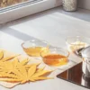 Cannabis leaves laid out on a cloth next to glass bowls and a saucepan during infusion preparation in a modern kitchen.