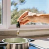 Cannabis oil being carefully added with a dropper to a pot on a kitchen stove