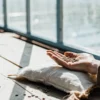 Hand holding cannabis seeds on a wooden table inside a greenhouse with natural sunlight