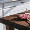 Colorful THC lollipops resting on a rustic wooden kitchen counter in natural sunlight.