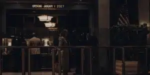 People entering a modern building lobby with security and opening sign January 2027.