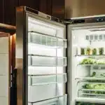 Cannabis leaves drying inside an open refrigerator used as a controlled environment for cold curing and preservation.
