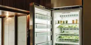 Cannabis leaves drying inside an open refrigerator used as a controlled environment for cold curing and preservation.