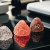 Different colored cannabinoid crystals on a reflective laboratory surface.