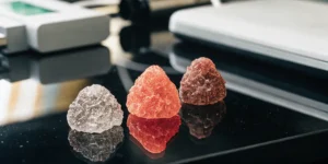 Different colored cannabinoid crystals on a reflective laboratory surface.
