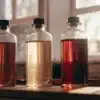 Three glass bottles with cannabis extract oils in different colors under natural sunlight.