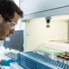 Laboratory technician analyzing cannabis samples with vials in a testing machine.