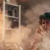 Person coughing in a smoky room after inhaling cannabis smoke.