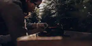 Scientist examining soil near cannabis plants in greenhouse environment.