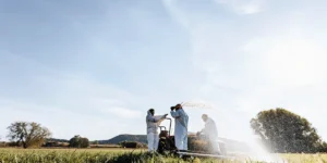 Agriculture team applying soil treatment in outdoor field with spraying equipment.