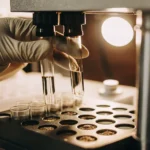 Gloved scientist handling cannabis sample test tubes in laboratory machine.