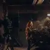 Camera operator filming inside an indoor cannabis grow room filled with flowering marijuana plants.