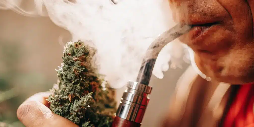 Cannabis vaporization device producing vapor beside a dense cannabis flower during consumption.
