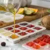 Cannabis-infused coconut oil being poured into silicone gummy molds with fruit ingredients.